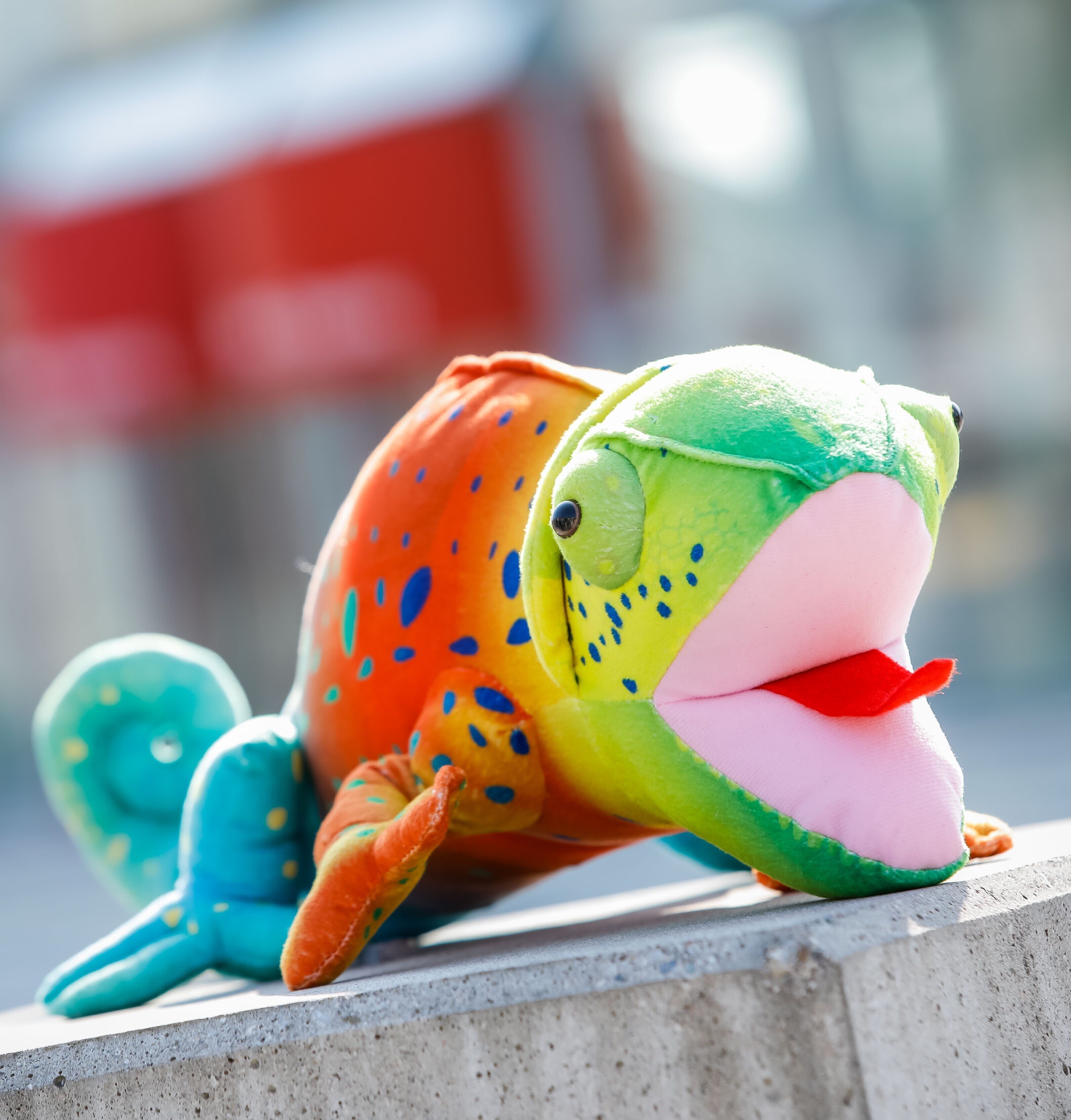 VIECON Maskottchen Gustav, ein buntes Chamäleon, liegt vor dem VIECON Messe Wien