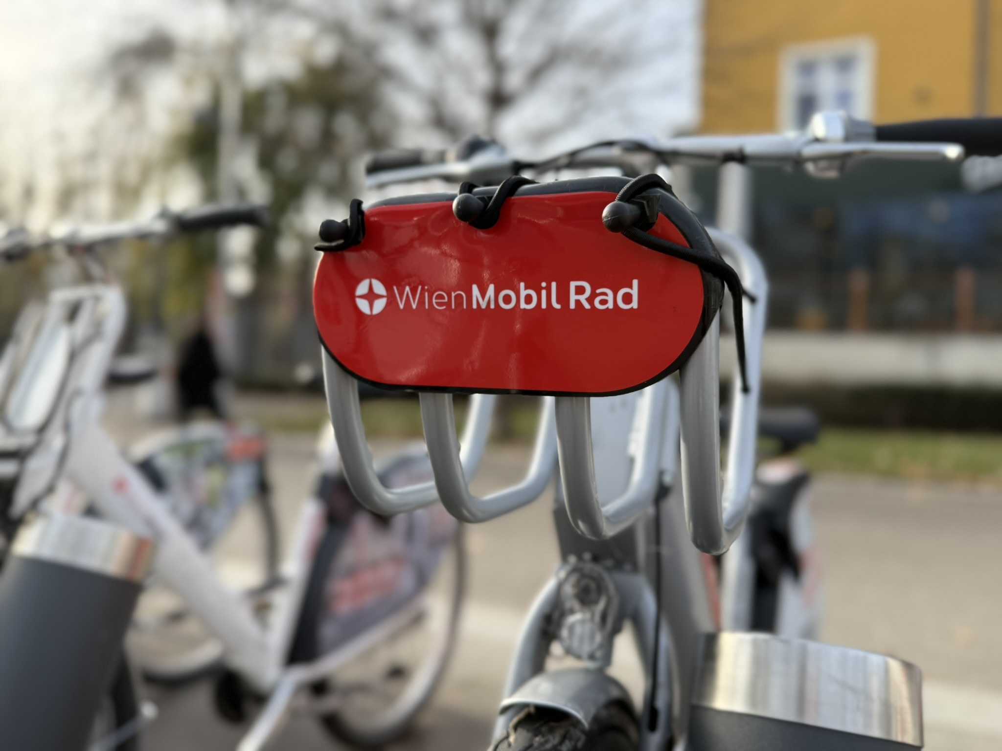 Close-Up eines Wien Mobil Fahrrads mit Bäumen im Hintergrund